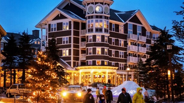 Ein großes, mehrgeschossiges Hotel mit einem markanten Glockenturm, einem überdachten Eingang und verschneiter Umgebung.
