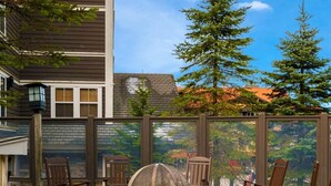 Eine Terrasse mit Feuerstelle, Steinsitzgelegenheiten und Blick auf eine bewaldete Gegend.