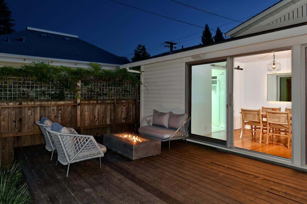 Eine Terrasse mit Sitzgelegenheiten und einem Feuerkorb, eine Glastür zur Essbereich im Innenbereich.
