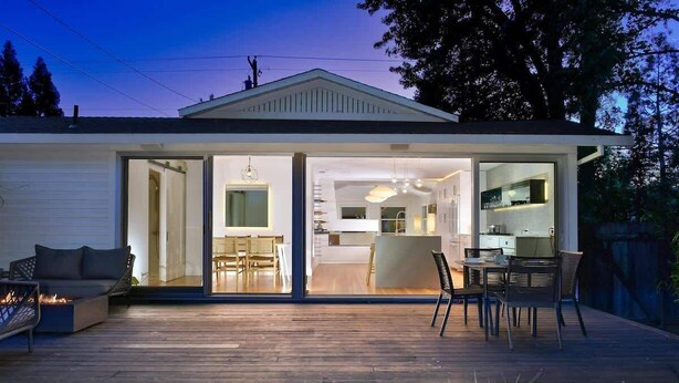 Una casa moderna con espacios integrados, una terraza con mobiliario exterior y una cocina a la vista.