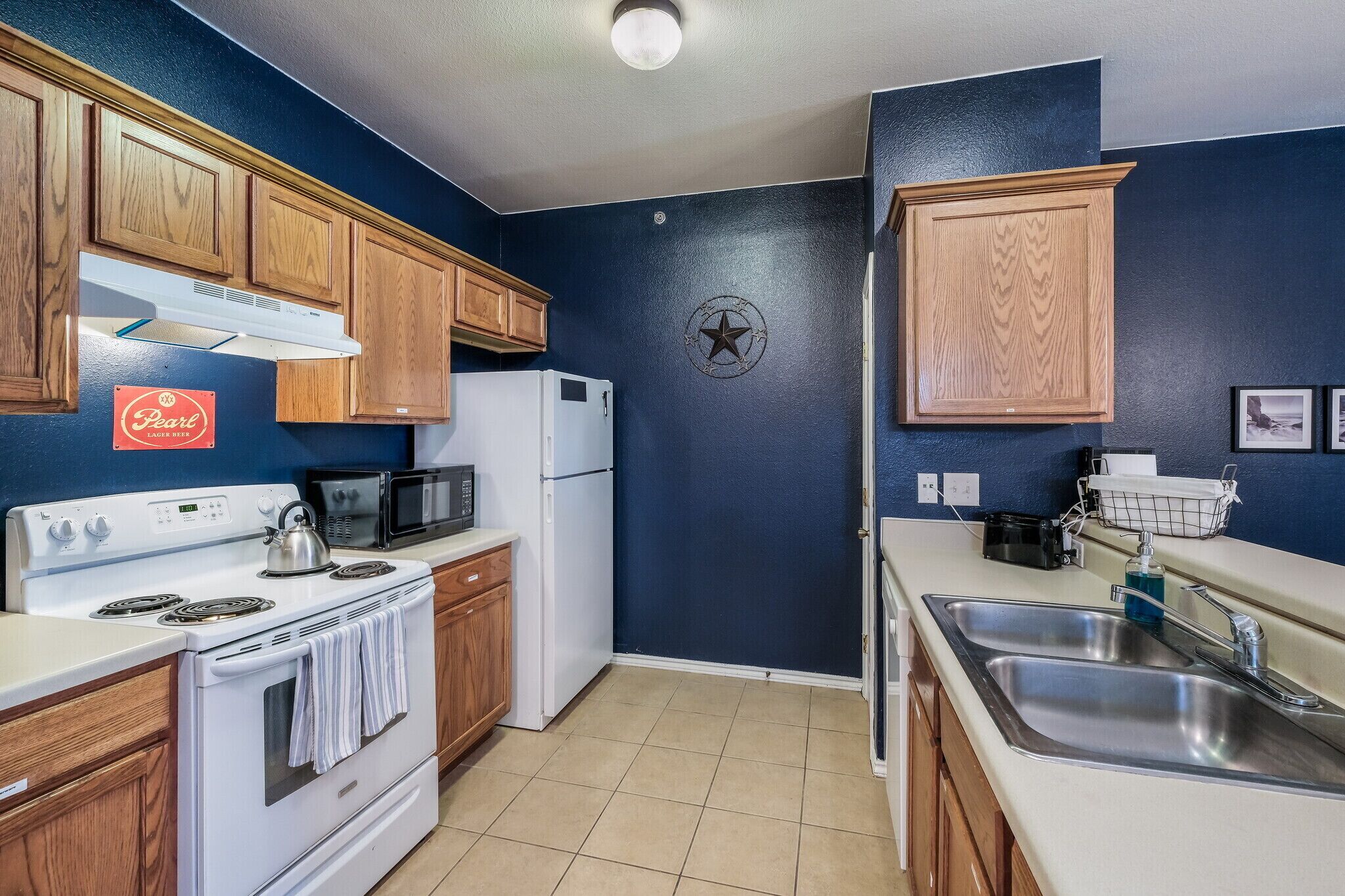 A kitchen with wooden cabinets, a white stove, a microwave, and a sink.