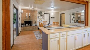 A modern kitchen with a central island, wooden cabinets, and a dining area with chairs and a table.
