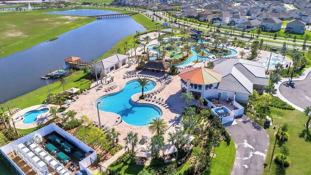 An aerial view of a resort with multiple swimming pools, a dock, and a residential area with houses. - Private Pool, Spa and Premium Resort Amenities Included! (Kissimmee)