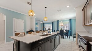 A modern kitchen with a central island, dark cabinetry, and pendant lighting. - Private Pool, Spa and Premium Resort Amenities Included! (Kissimmee)