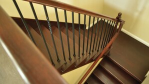 Una escalera de madera con barandilla y descansillo.