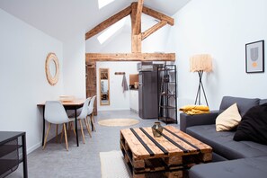 Un salon moderne avec une table basse en bois, un canapé gris et un coin repas comprenant des chaises et une table.