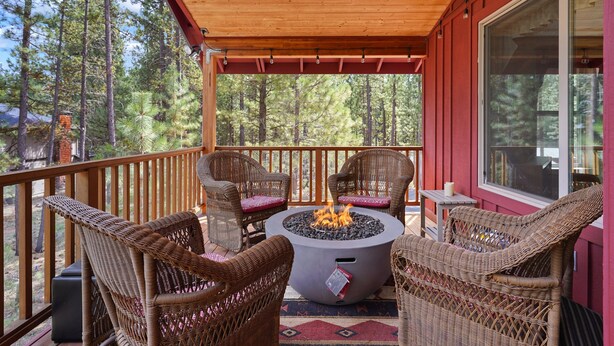 A covered outdoor seating area with wicker chairs and a central fire pit. - 164 Jillian - Private, Peaceful Near Deschutes River, Hot Tub, Fenced Yard, Ping Pong, & Foosball (Sunriver)