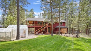 A two-story cabin with a wooden deck and a covered patio area. - 164 Jillian - Private, Peaceful Near Deschutes River, Hot Tub, Fenced Yard, Ping Pong, & Foosball (Sunriver)
