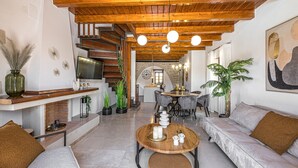 A modern living room with a fireplace, wooden ceiling, and a dining area with a chandelier. - Dim Luxury Villa - With Private Pool (Margarites)