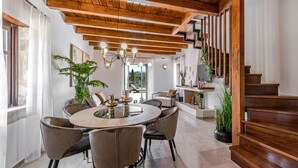 A spacious dining area with a round table and chairs, wooden ceiling beams, and a staircase. - Dim Luxury Villa - With Private Pool (Margarites)