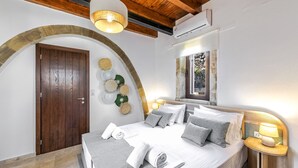 A bedroom with a wooden door, a bed with pillows, a bedside table with a lamp, and a large mirror. - Dim Luxury Villa - With Private Pool (Margarites)