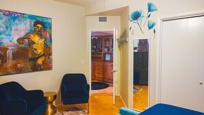 Ein Wohnzimmer mit einem blauen Sofa, einem kleinen runden Tisch und einem Bild an der Wand.