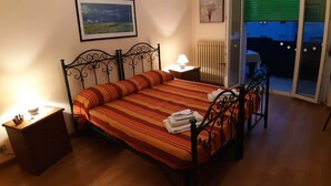Un dormitorio con cama, mesita de noche, lámpara y ventana con vistas al exterior.