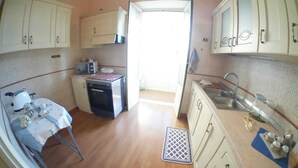 Una cocina funcional con mesa, estufa, lavaplatos y armarios.