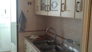 Una cocina con gabinetes blancos, un lavamanos de acero inoxidable y un tapete azul en el suelo.