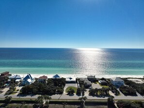 A coastal property with a beach view, multiple houses, and a clear sky.