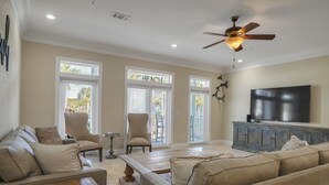 A spacious living room with a high ceiling, a ceiling fan, a flat-screen TV, and a large window with blinds. - Snowbird Specials-2 Minute Walk Private Beach-3 Pools - Gulf Place (Santa Rosa Beach)