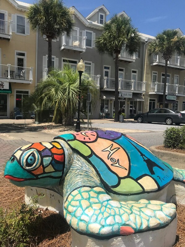 A colorful turtle sculpture in a public space with a building in the background.