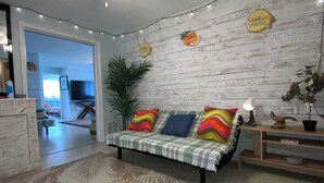 A living room with a sofa, a ceiling fan, a plant, and a wall with wooden panels. - MANASOTA BEACH 1 MINUTE AWAY! (Englewood)