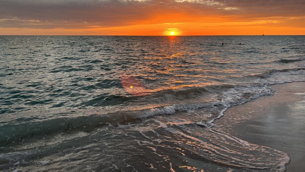 A sunset over a calm sea with waves gently touching the shore. - MANASOTA BEACH 1 MINUTE AWAY! (Englewood)