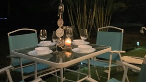 An outdoor dining area with a table set for two, surrounded by chairs, under a canopy with string lights. - MANASOTA BEACH 1 MINUTE AWAY! (Englewood)