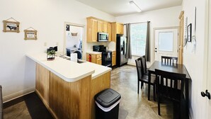 A modern kitchen with wooden cabinets, a central island, and a dining area with a table and chairs.