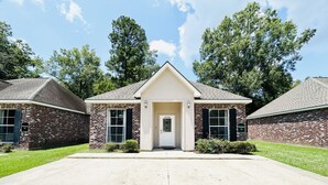 A two-story building with a central entrance, brick exterior, and a small front yard.
