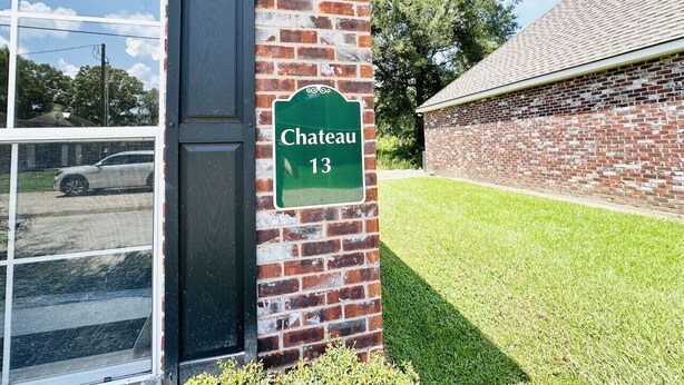 A brick building with a green sign reading "Chateau 13" on a clear day.