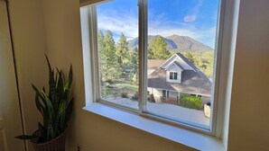 Una ventana con vistas a una casa y montañas.