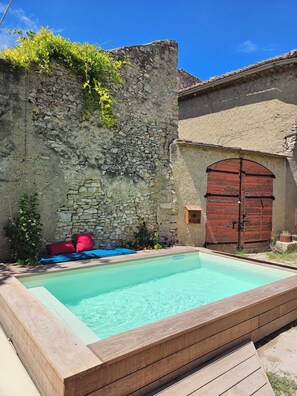 Un mur de pierre avec un banc en bois et une porte rouge.