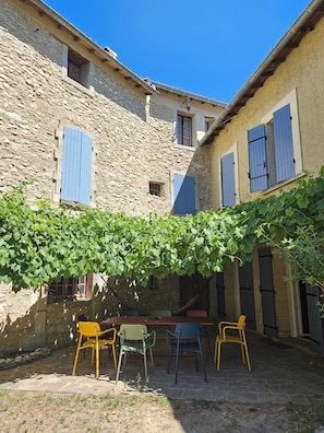 A courtyard with stone buildings, a table, and chairs.