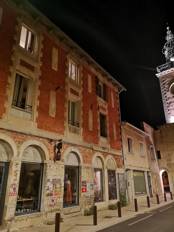 Un bâtiment historique doté de fenêtres en arc de cercle et d’une façade en briques, où l’on peut apercevoir un mannequin dans la vitrine.