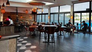 Un restaurante moderno con interior de madera, ventanas amplias y vista a una piscina.