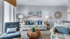 Un salon avec un canapé, des fauteuils, une table basse et un tableau accroché au mur.