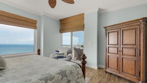 Une chambre avec un grand lit, une armoire en bois et une vue sur la mer.