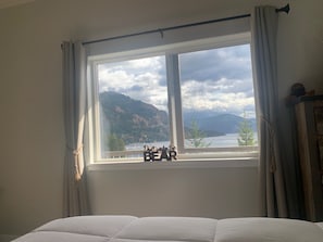 Un dormitorio con un ventanal que ofrece vistas a montañas y a un lago.