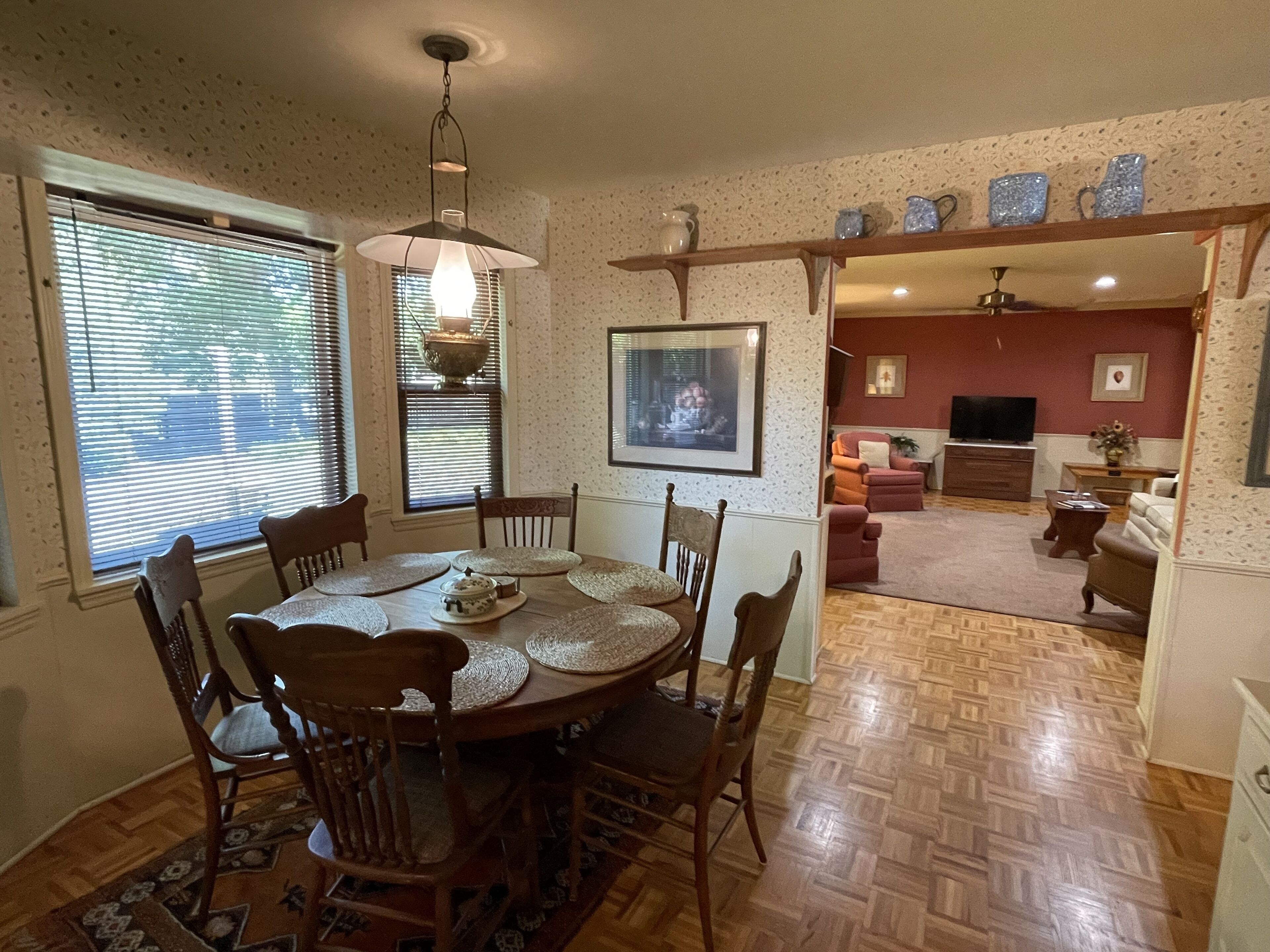 A dining area with a round table, chairs, and a hanging light fixture.