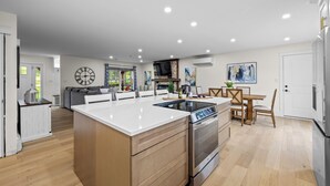 Une cuisine moderne dotée d’un îlot central, d’un four encastré et d’un coin repas avec une table et des chaises.