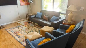 Ein Wohnzimmer mit einer Couch, zwei Sesseln, einem Couchtisch und einem Teppich.