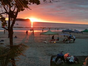 Une scène de plage avec des personnes qui se promènent, des tentes et des chaises de plage.