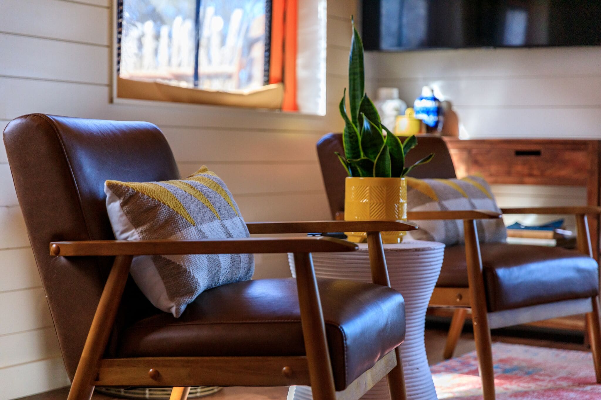 A cozy living room with a brown leather chair, a wooden coffee table, and a potted plant.