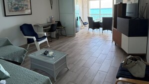 Un vaste espace de vie comprenant un balcon, une table à manger et un meuble pour la télévision.