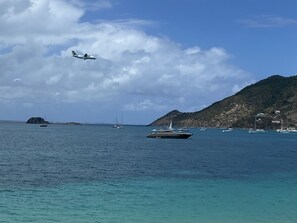 Eine Küstenlandschaft mit Booten, einem Segelboot und einem Jet über dem Wasser.