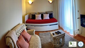 Une chambre confortable avec un lit à la forme arrondie, un canapé, une petite table et un téléviseur.