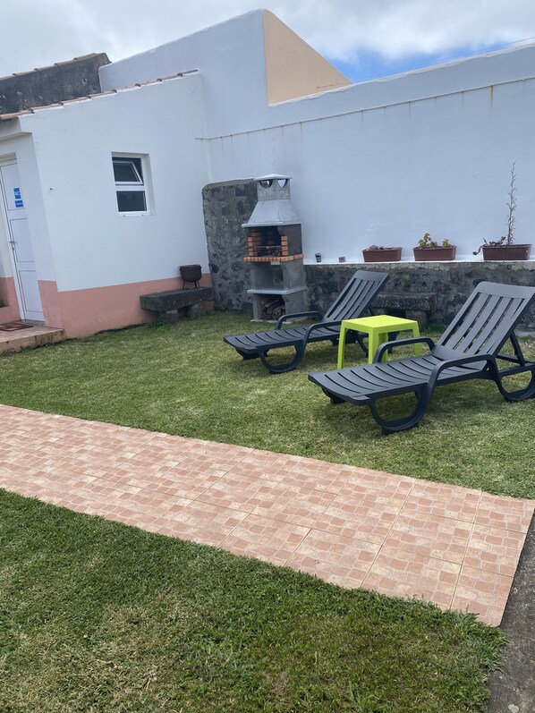 Un patio con una parrilla, asientos exteriores y una pequeña mesa.