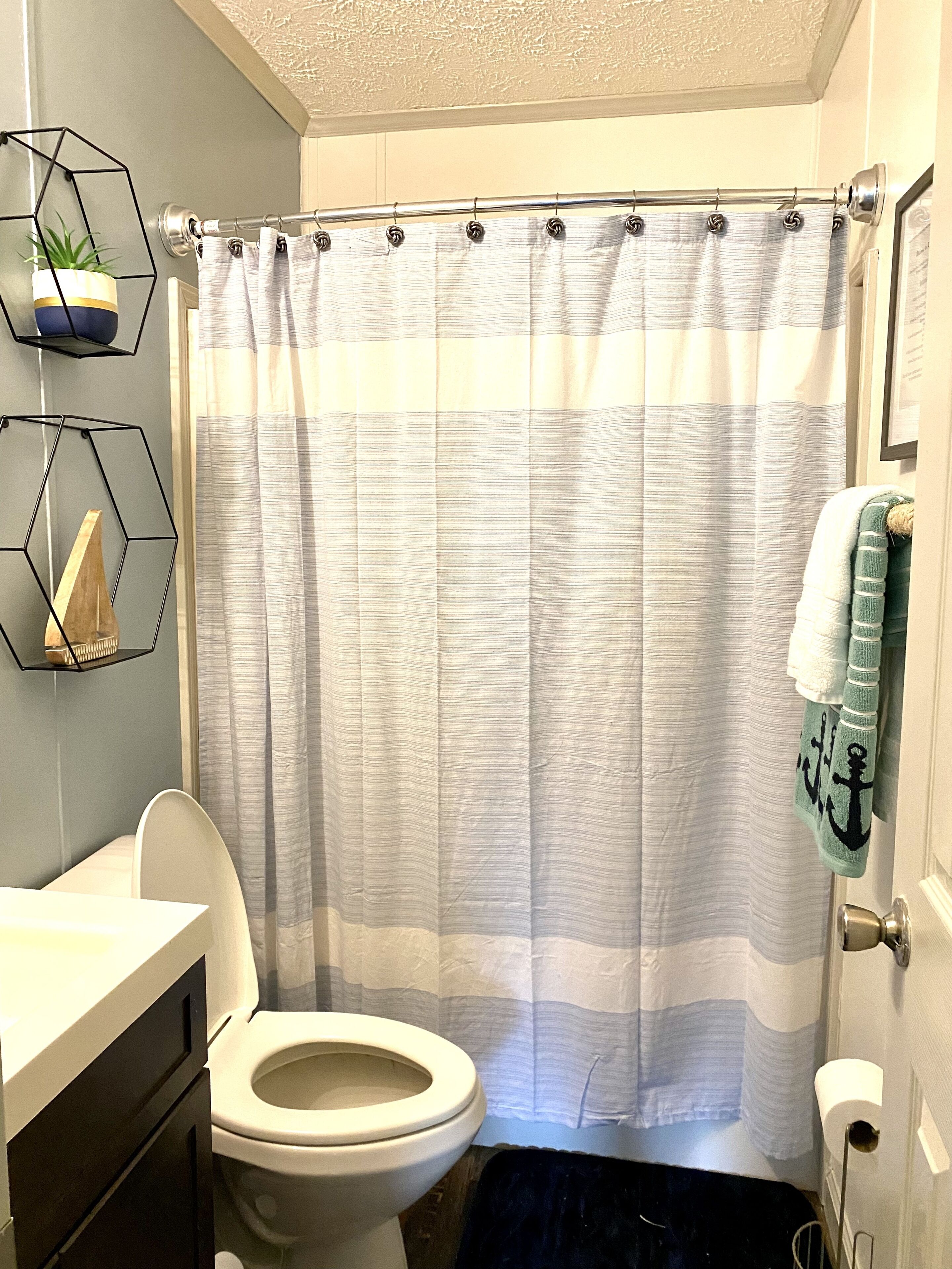 Une salle de bain équipée d’un rideau de douche, de toilettes, d’un lavabo et d’un porte-serviettes.