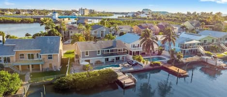 A residential area with houses near a body of water, docks, and a bridge in the background.