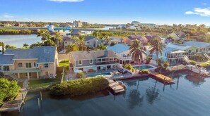 A residential area with houses near a body of water, docks, and a bridge in the background. - Waterfront Oasis, Heated Pool, Dock, Golf Cart & Chef’s Kitchen (Indian Rocks Beach)