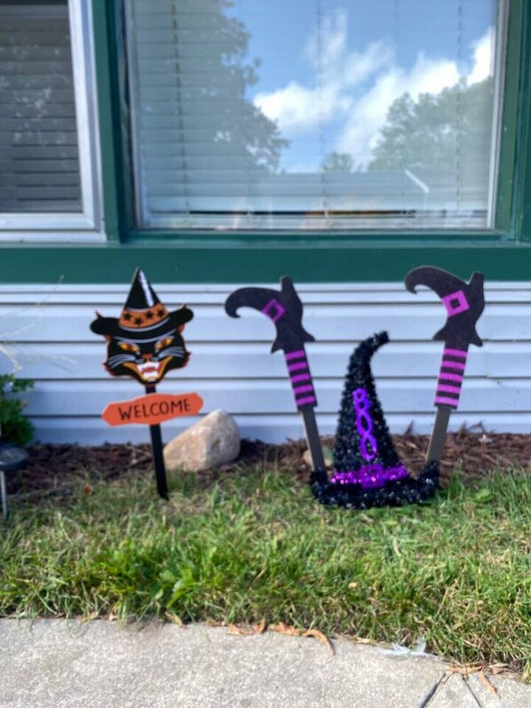 A house with a 'WELCOME' sign and two witch-themed decorations in front. - Beach House Walking Distance to Everything (Caseville)