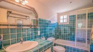 A bathroom with a sink, toilet, and bathtub, featuring blue-tiled walls and a window. - Villa with pool and sea view in Grimaud (GRIMAUD)